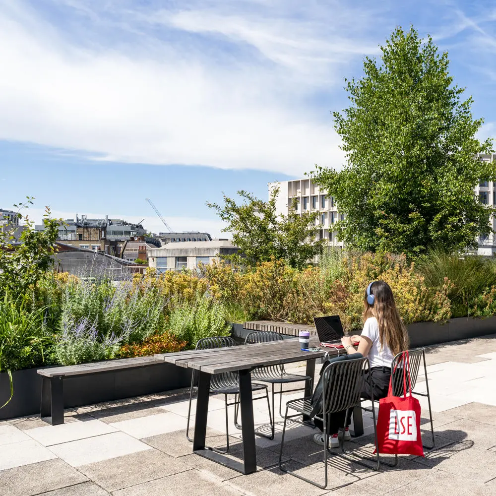 A student working on LSE rooftop with an LSE totebag