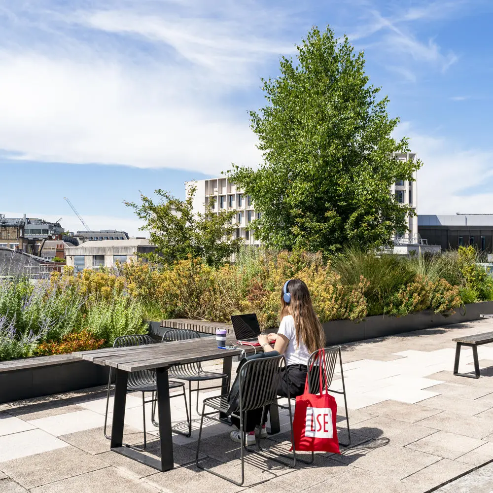 A student working on LSE rooftop with an LSE totebag