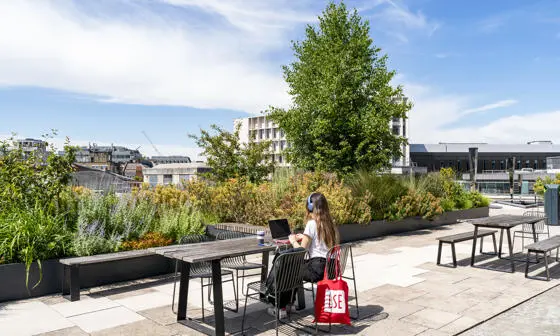 A student working on LSE rooftop with an LSE totebag