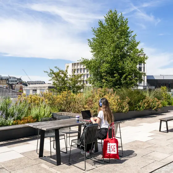 A student working on LSE rooftop with an LSE totebag