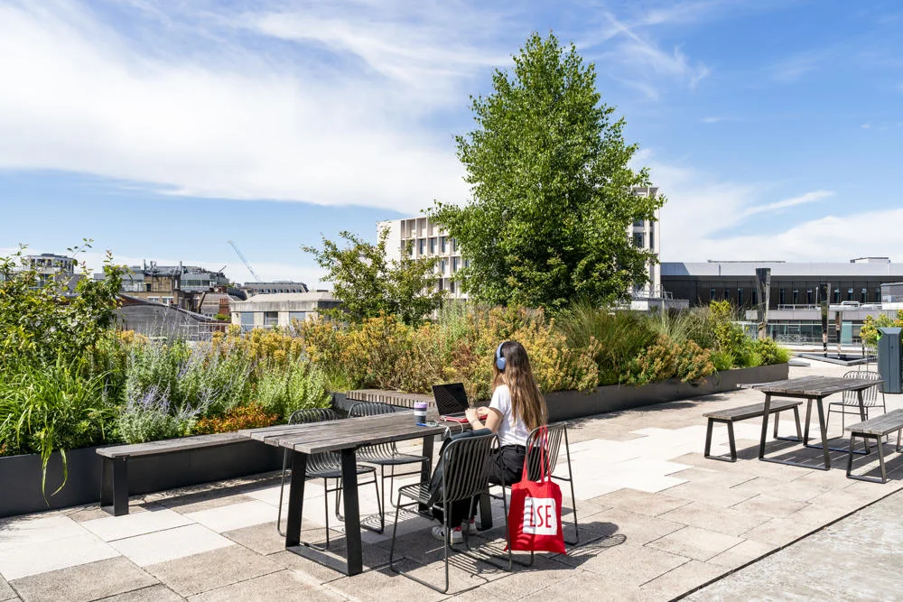 A student working on LSE rooftop with an LSE totebag