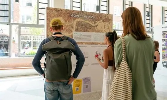 Three people looking at a board with information on it