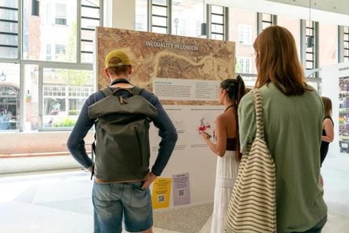 Three people looking at a board with information on it