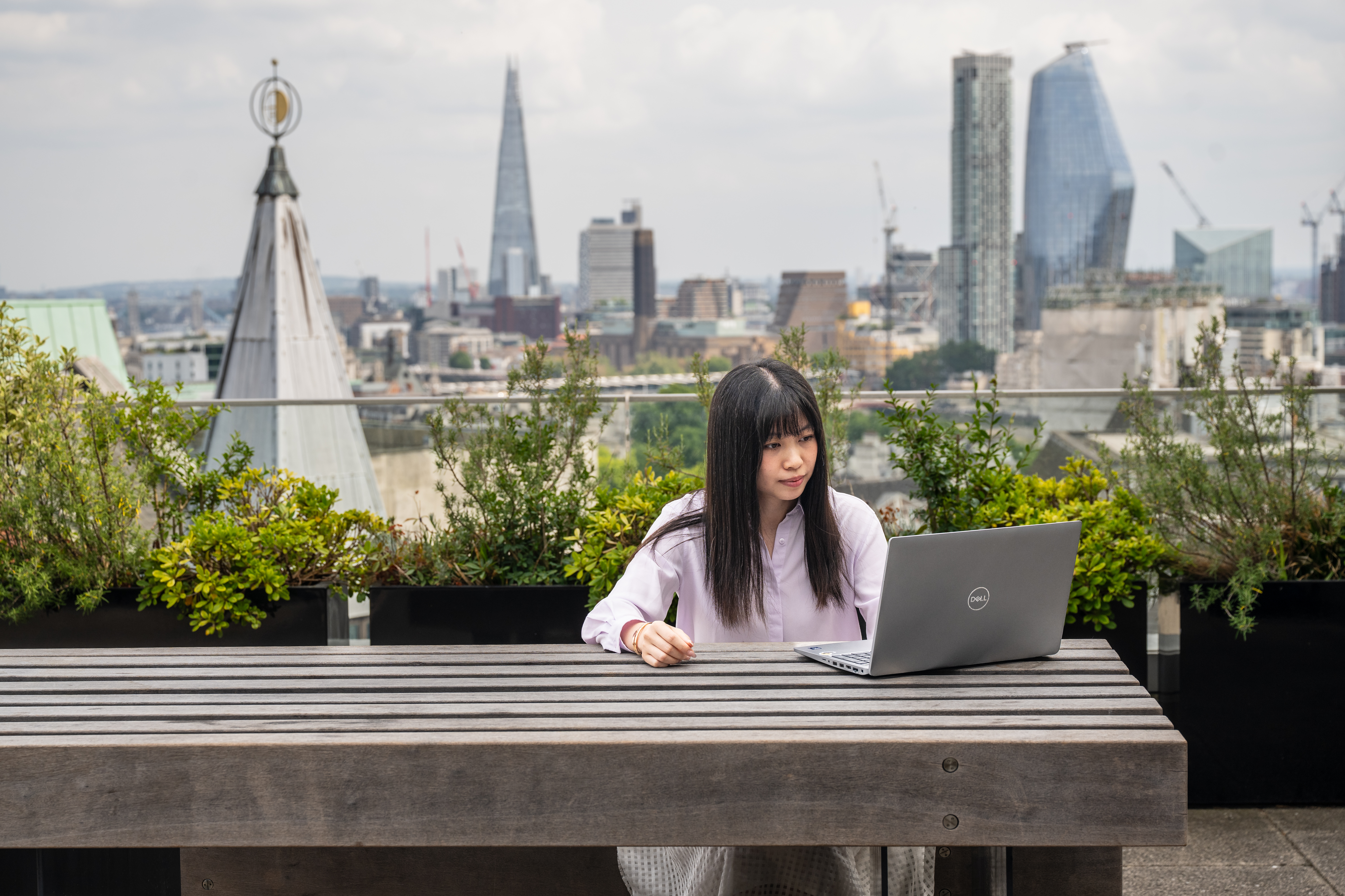 Student using a laptop on a rooftop overlooking central London