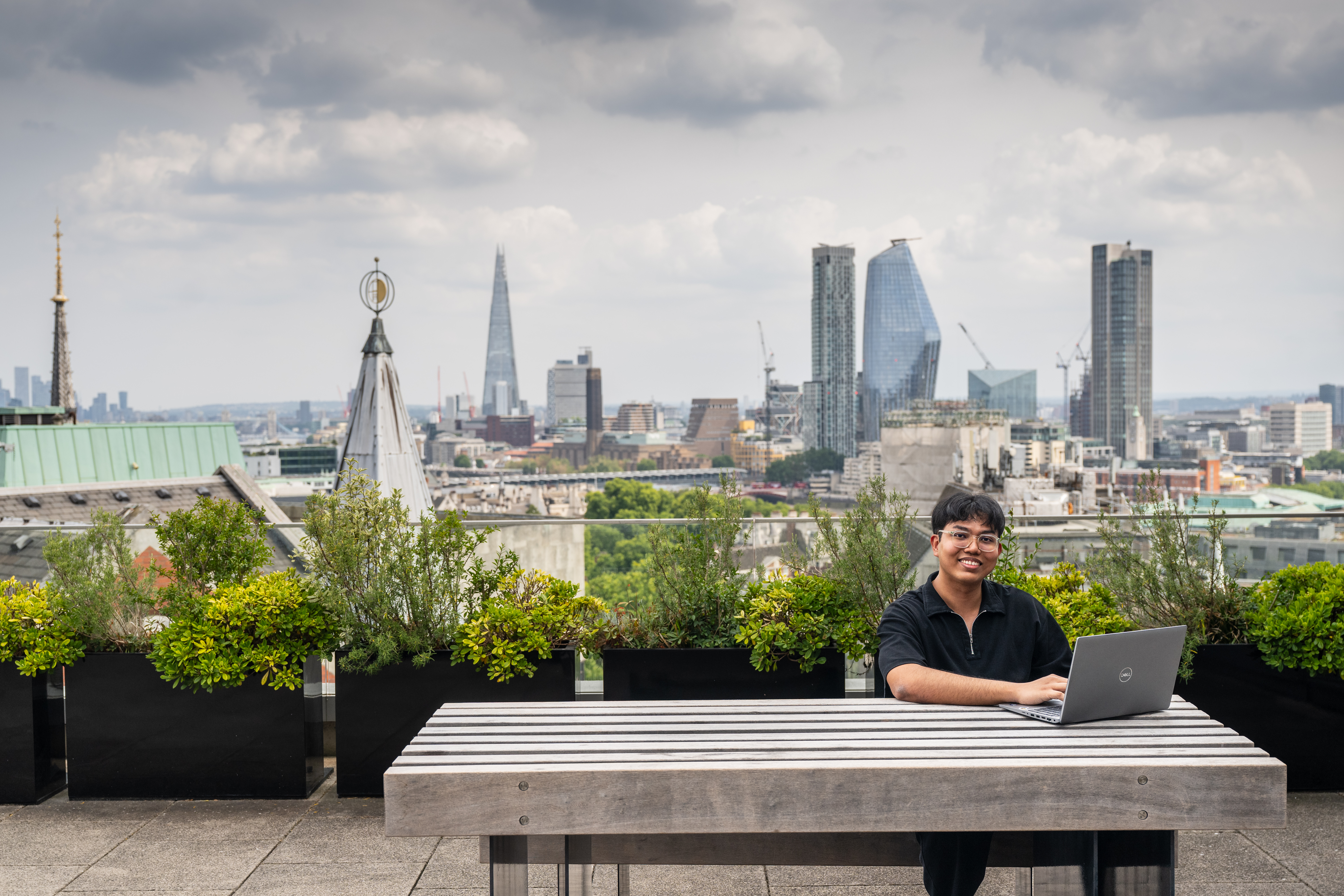 Student using a laptop on a rooftop overlooking central London