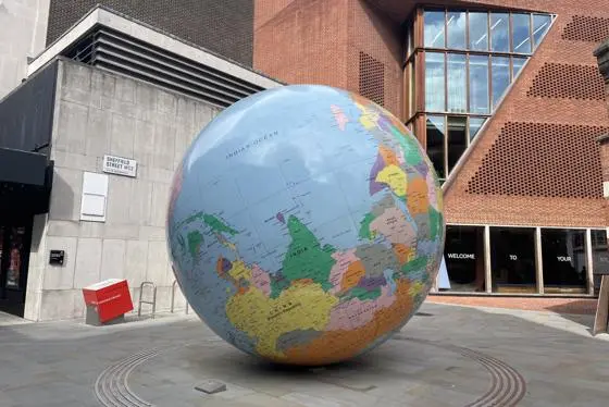 LSE's World Turned Upside Down sculpture next to the Saw Swee Hock building on the LSE campus