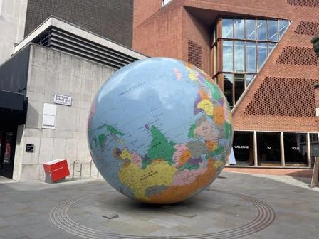 LSE's World Turned Upside Down sculpture next to the Saw Swee Hock building on the LSE campus