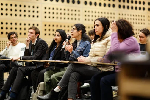 Audience members at LSE lecture, one person holding a microphone and asking a question
