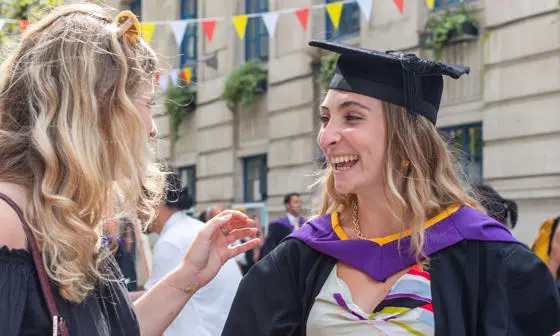 Two students talking to each other after their graduation ceremony at LSE.