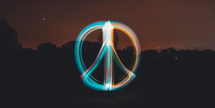 Glowing peace symbol drawn with light in the night, symbolising hope and calm.