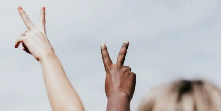 Two people holding up the peace sign with their hands