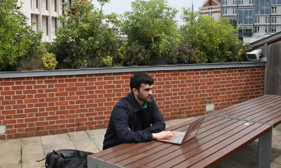 LSE student working on his laptop on the roof terrace of the LSESU Saw Swee Hock Centre