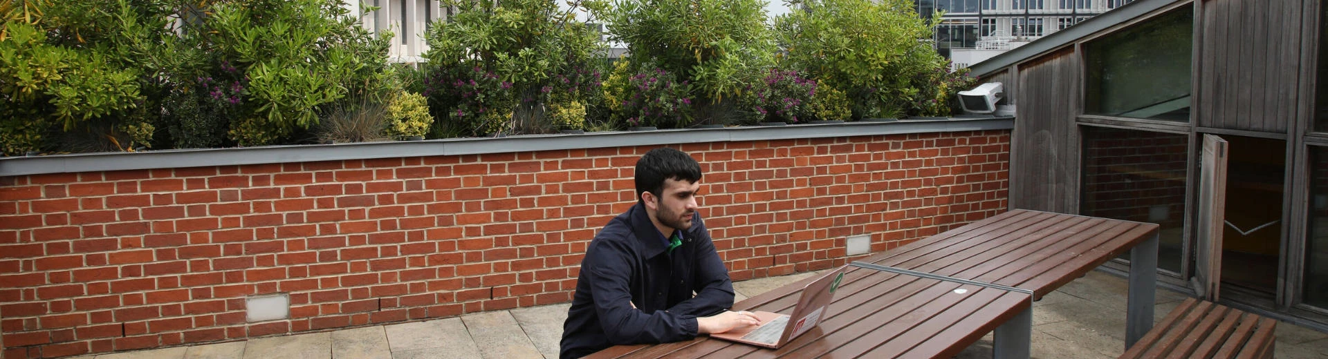 LSE student working on his laptop on the roof terrace of the LSESU Saw Swee Hock Centre