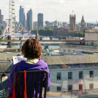 the back of a students head as she reads a paper overlooking London 