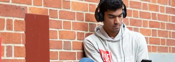 LSE student sitting in listening to music on his smartphone