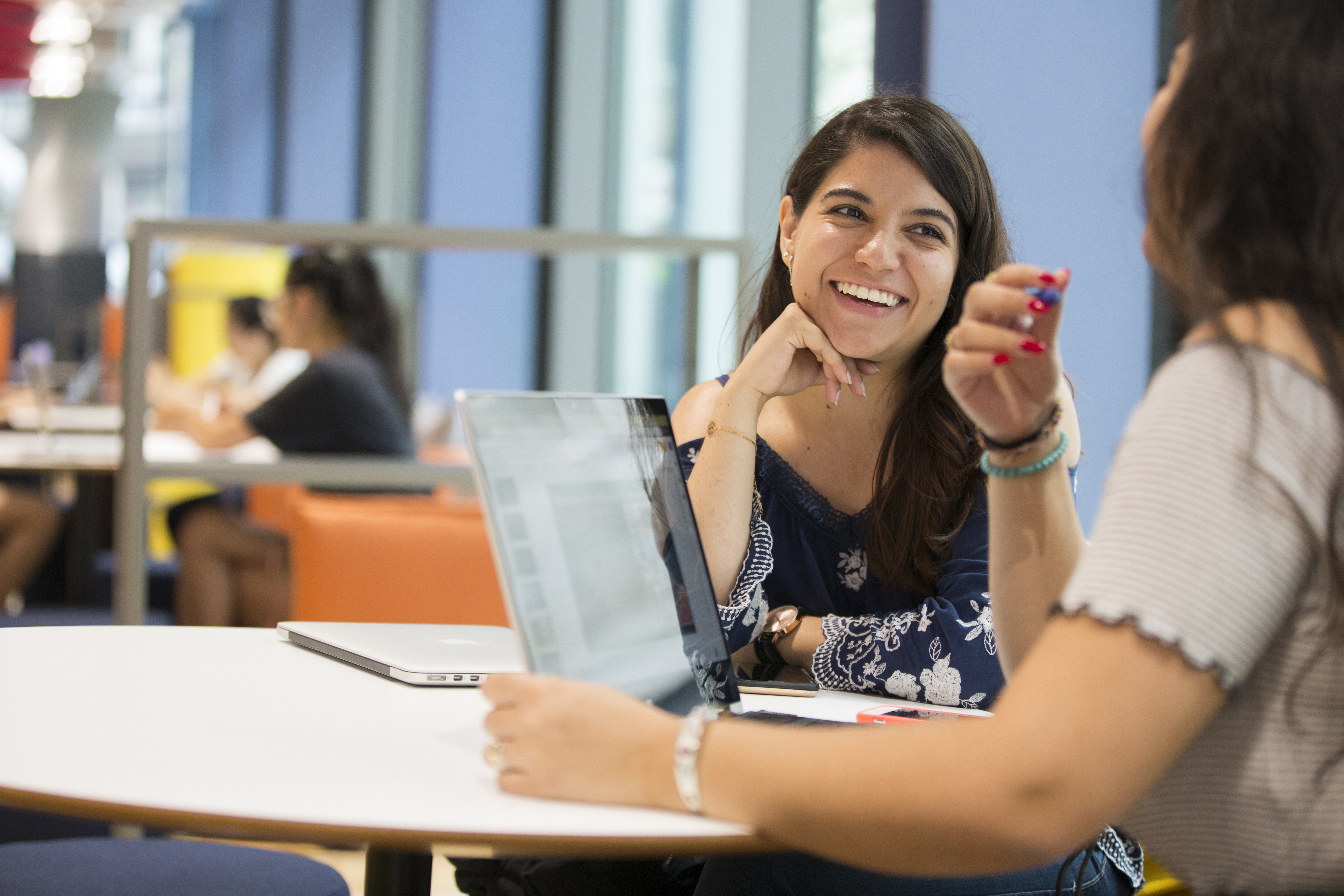 Student discussion at a table with laptops in a campus study space