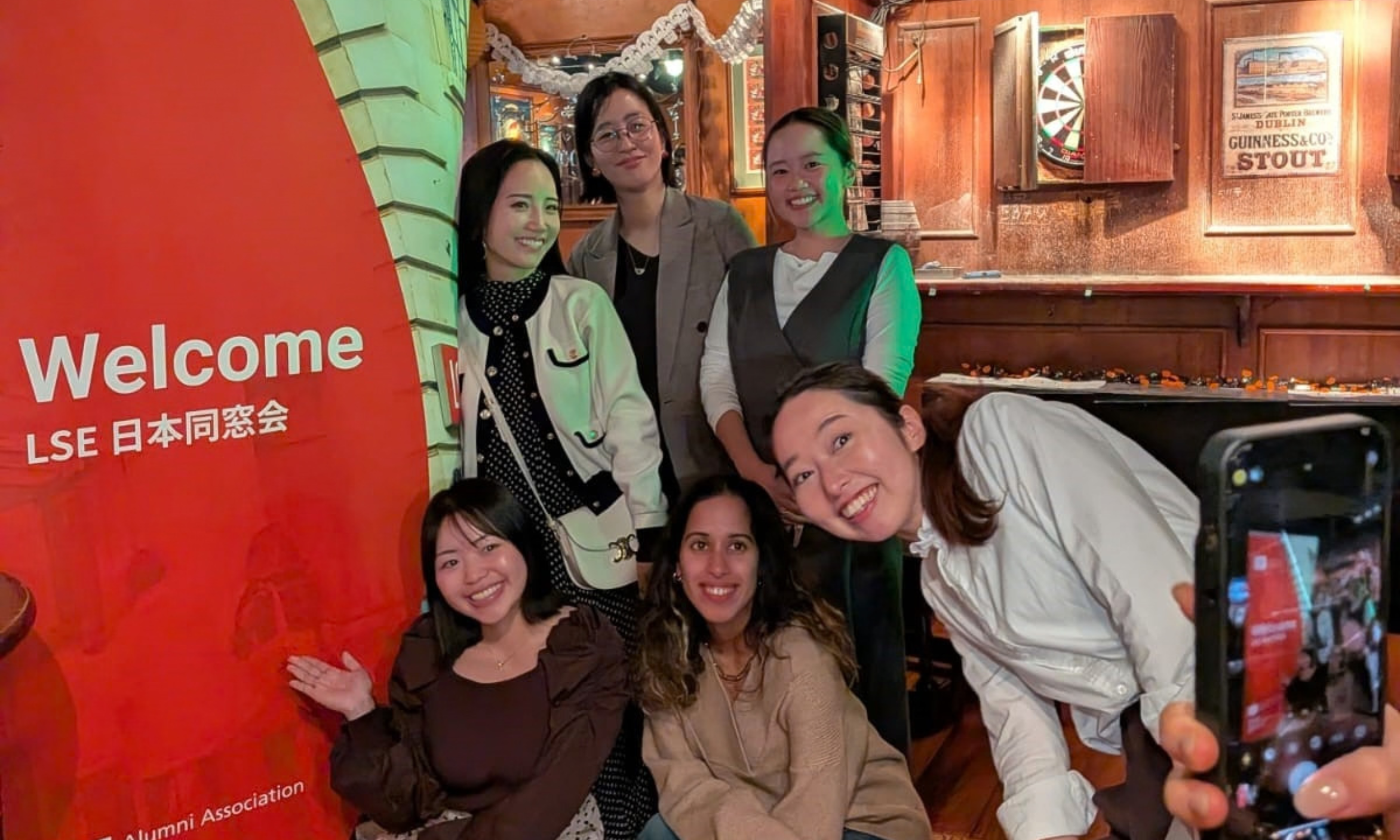 Alumni pose beside a banner during Welcome to the City Japan.