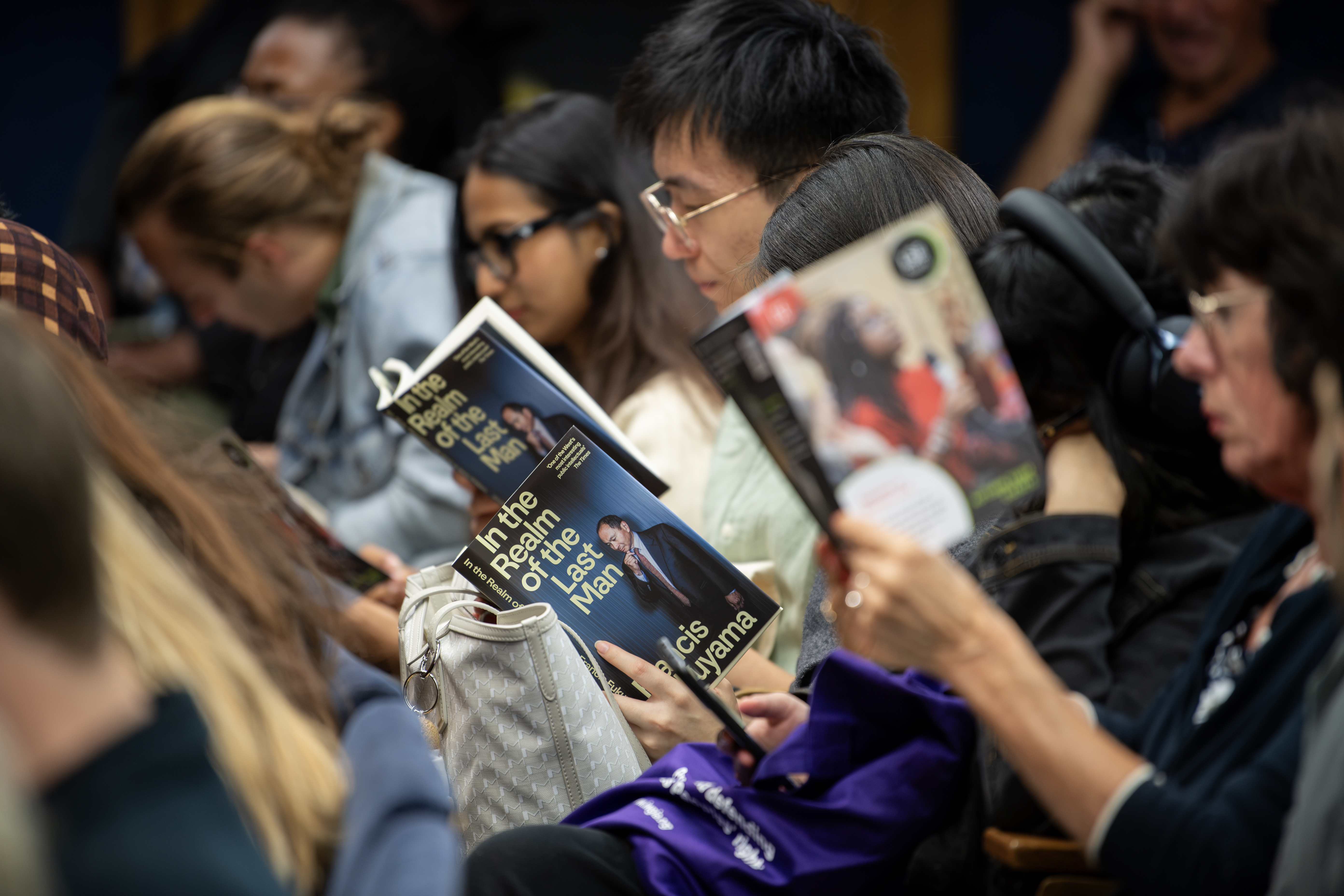 Audience members reading book by Prof Francis Fukuyama