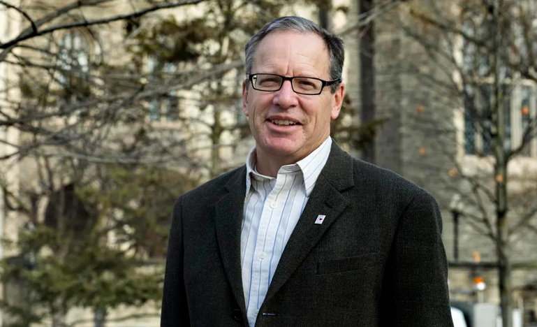 Mark Bonham stands outside wearing a suit