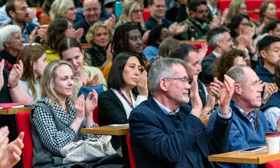 rows of people clapping seated in a lecture theatre