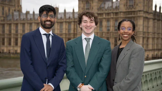 Three students in front of the UK Houses of Parliament