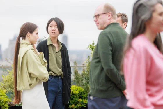 a group of five academics stand and have conversations in groups