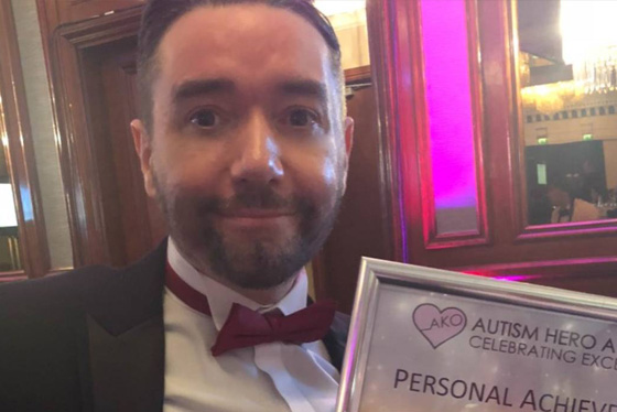 Mickey Mayhew holds a certificate recognising his achievements as a person with autism
