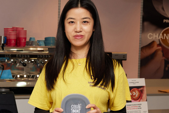 Mingqiao Zhao stands in a cafe holding her CauliBox