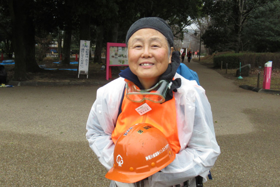 Naomi stands with her volunteer helmet outside a forest