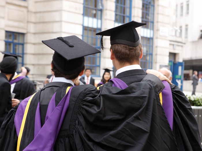 Two male graduates at graduation with their backs to the camera positing for a photo