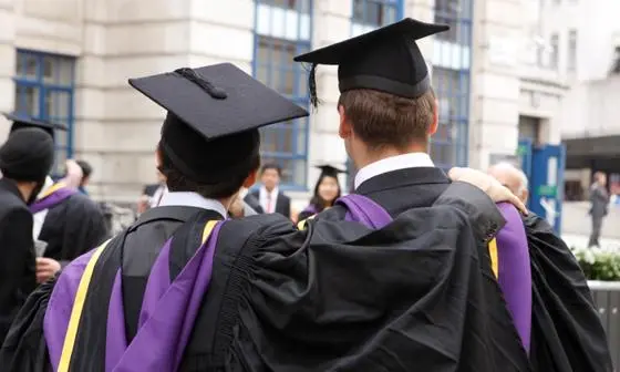 Two male graduates at graduation with their backs to the camera positing for a photo