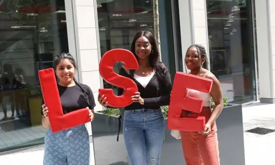 Three students holding LSE logo