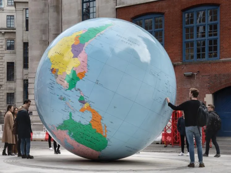 People look at an upside-down globe on the LSE campus