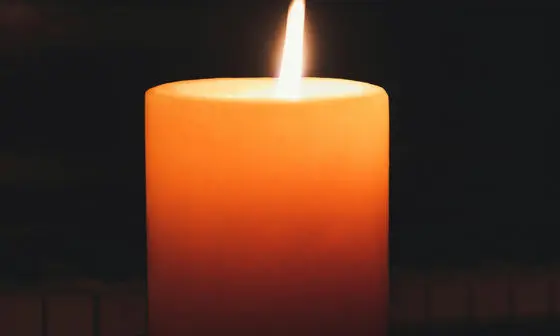 A single candle burns in the dark