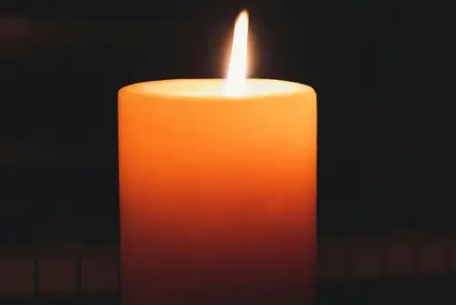 A single candle burns in the dark