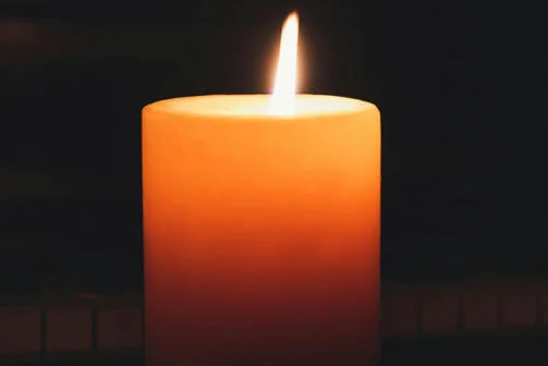 A single candle burns in the dark