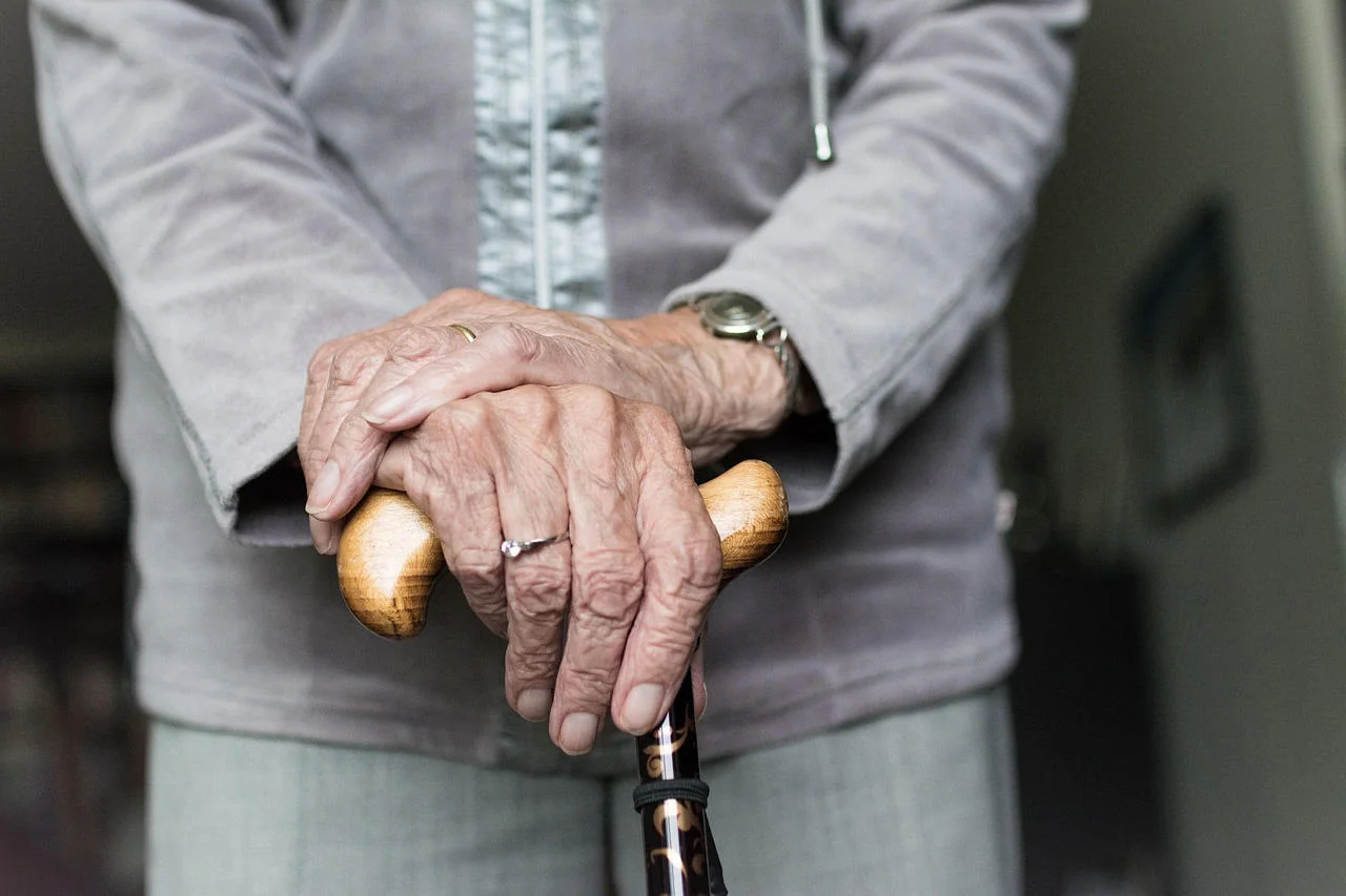 Older woman's hands holding walking stick