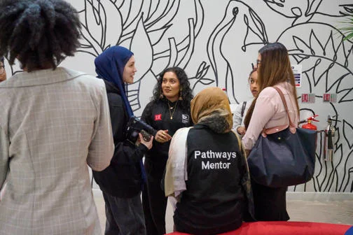 A group of five students talking to a mentor.