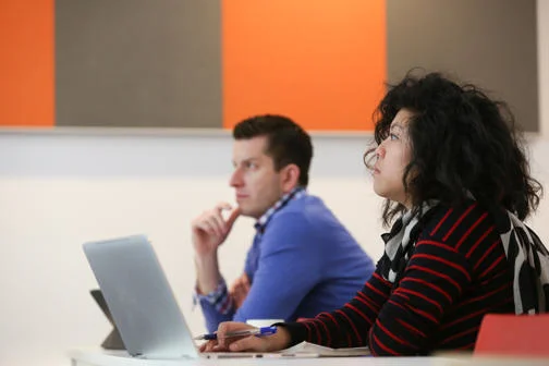 Two people sat in an LSE classroom with one in front of her laptop