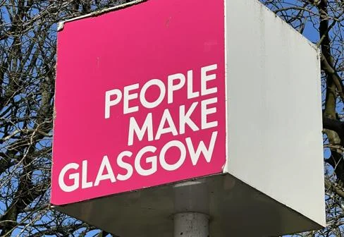 "People make Glasgow" slogan on a sign with a pink background