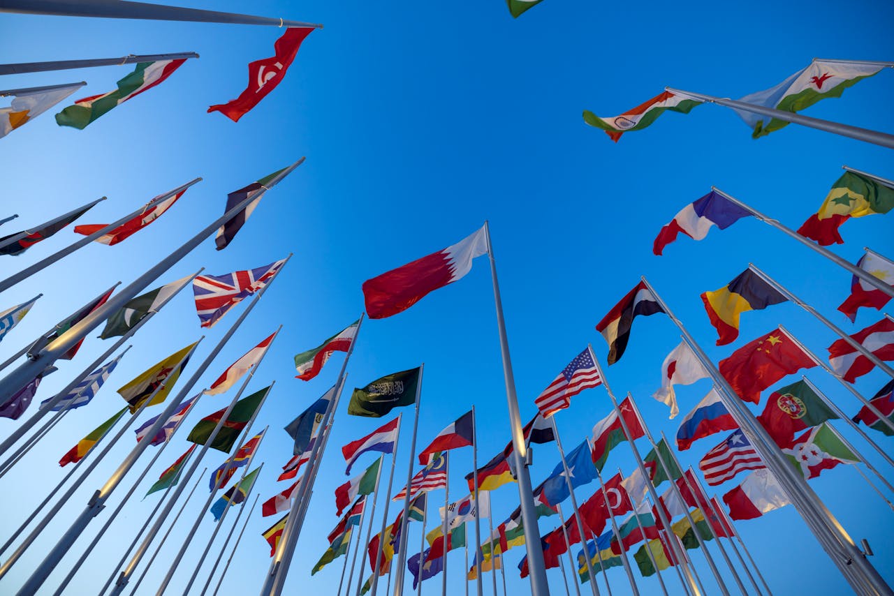Multiple national flags from around the world against a bright blue sky