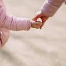 Crop daughter standing hand in hand with mother in city