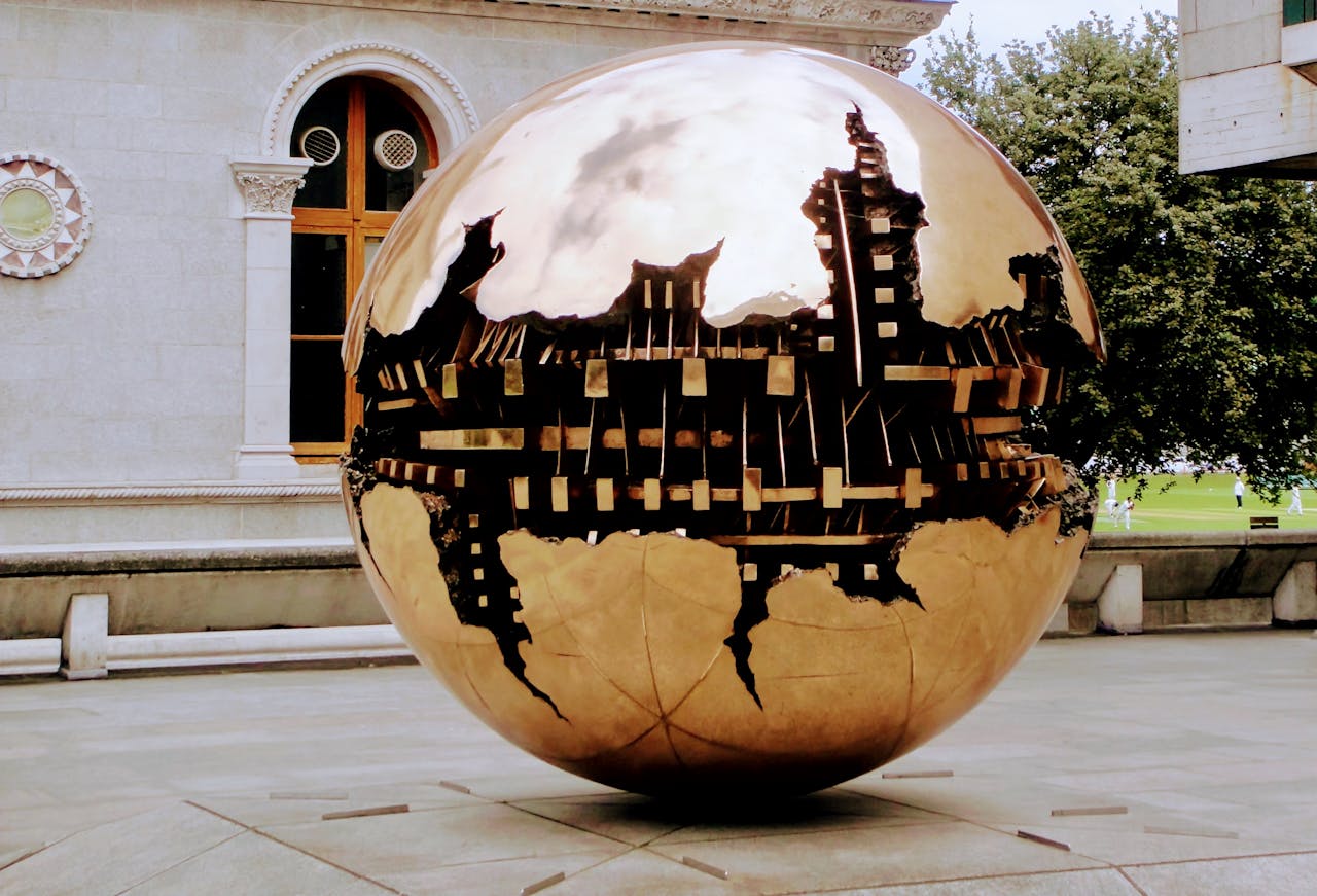 Large polished spherical sculpture with cut-out world map sections