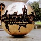 Large polished spherical sculpture with cut-out world map sections