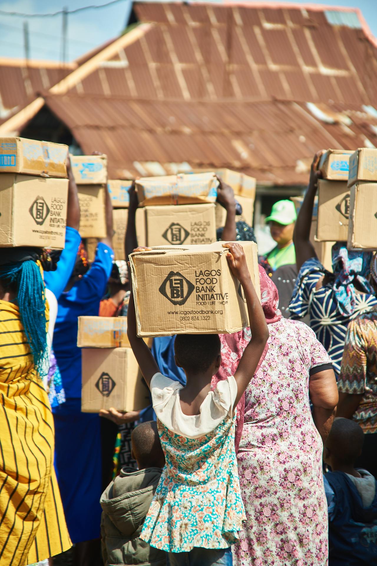Group of people carrying cardboard food aid boxes on their heads 