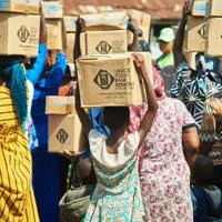 Group of people carrying cardboard food aid boxes on their heads