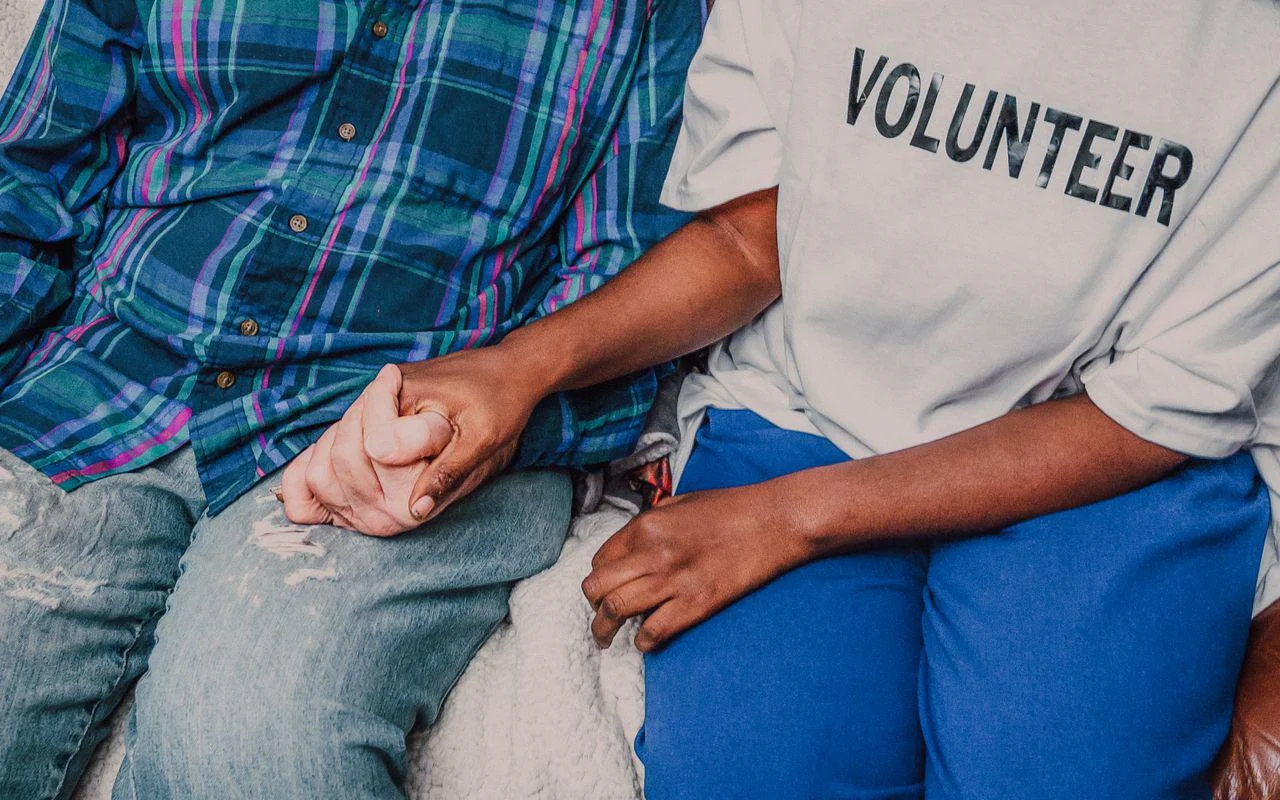 A volunteer holding hands with an elderly person.