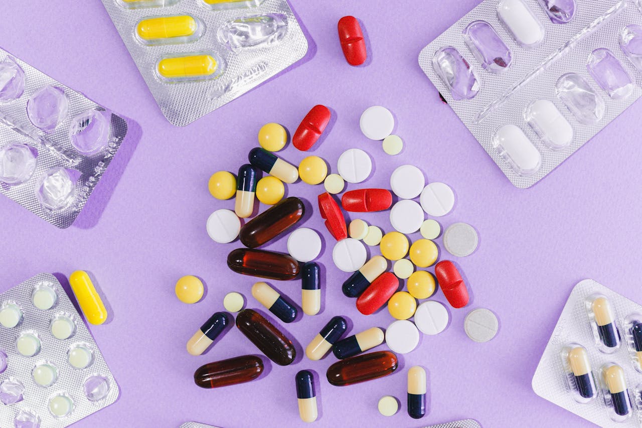 Top-down view of mixed capsules, tablets, and soft gel pills in various colours