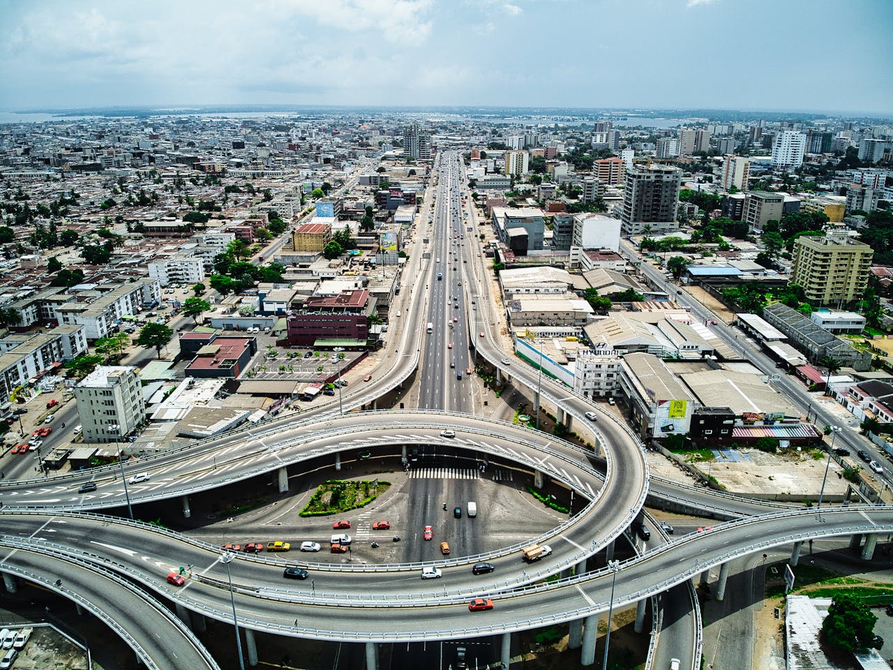 Aerial view of a multi-level highway interchange with cars and surrounding buildings in a dense urban area.