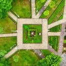 Top-down view of a landscaped park featuring intersecting paved walkways, green lawns, trees,